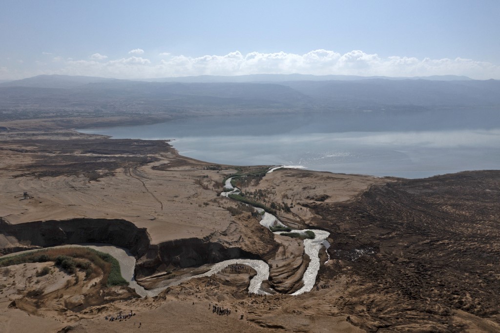 Israeli hikers walk on hills near where the Jordan River pours into the Dead Sea, close to the occupied West Bank city of Jericho, in October 2022 (AFP)