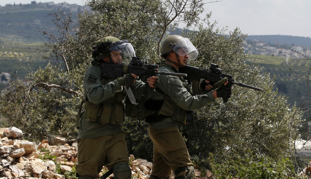 Israeli soldiers aim at Palestinian protesters in Kfar Qaddum on 19 April (AFP)