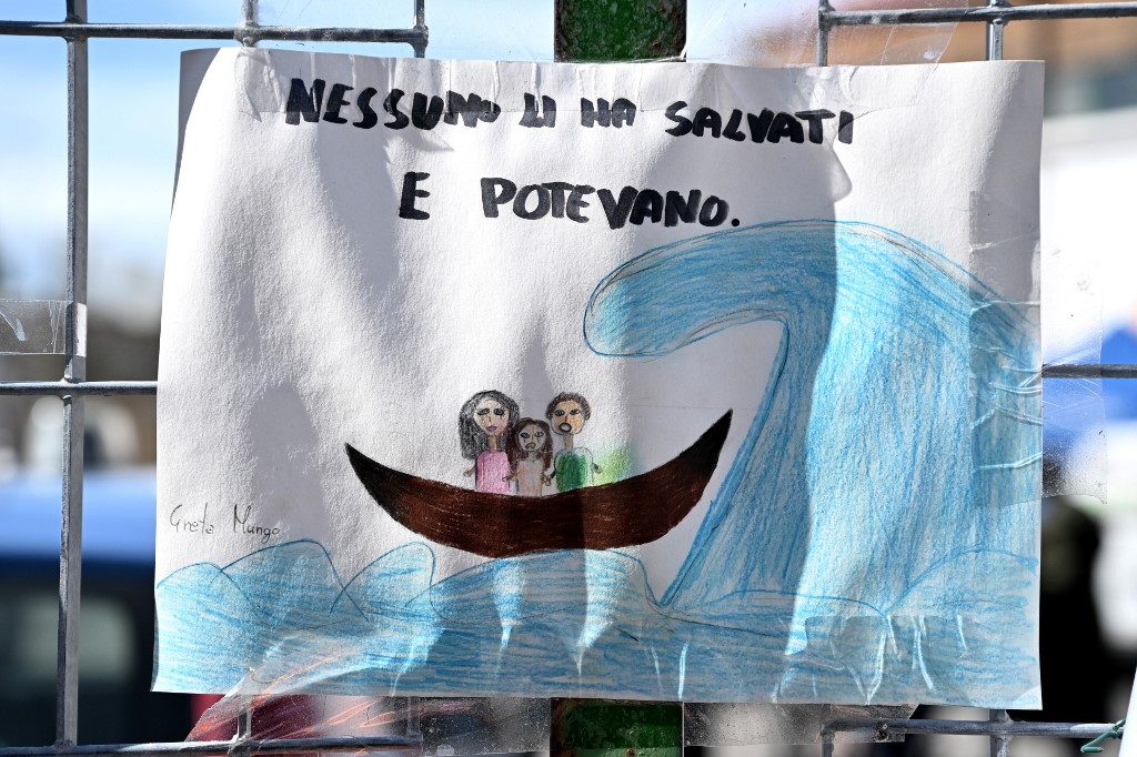 A drawing with a caption in Italian reads: ‘No one saved them and they could,’ after a boat sank off the coast of Calabria weeks earlier, on 9 March 2023 (AFP)