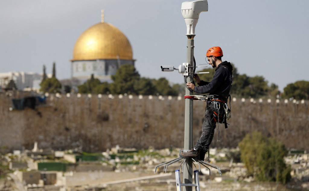 An Israeli technician installs a surveillance camera in occupied East Jerusalem in 2019 (AFP)