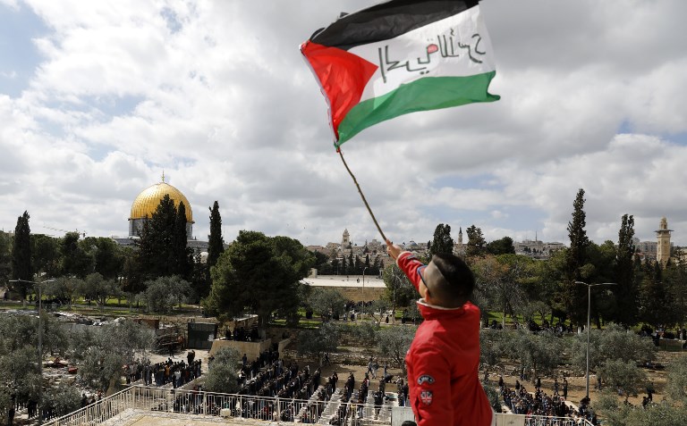 A Palestinian boy waves a national flag in Jerusalem on 15 March (AFP)