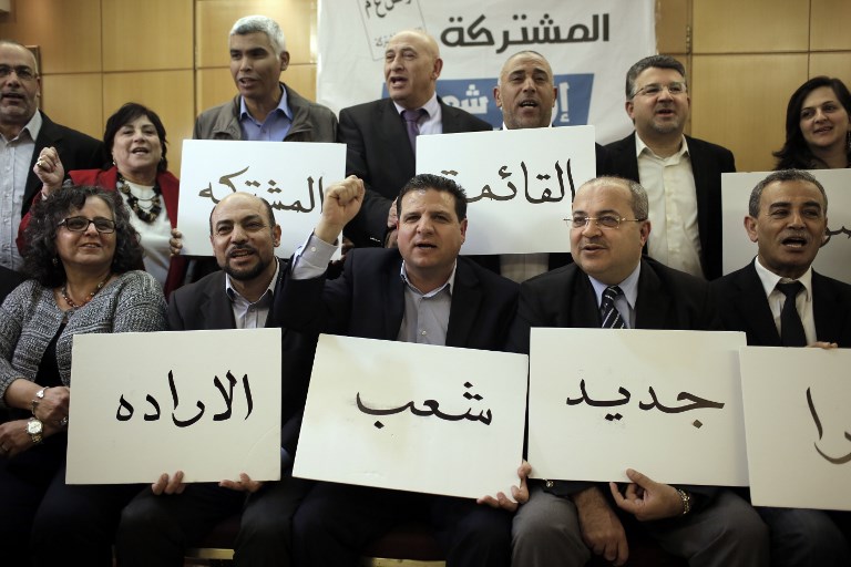 Israeli Arab political leaders hold placards urging voters to endorse the Joint List and usher in ‘a new tomorrow’ ahead of the 2015 elections (AFP)