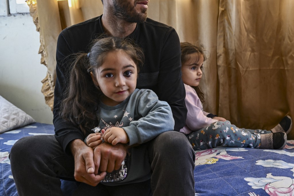 Members of a displaced family sit in a bed in a small house in Yerevan on October 5, 2023. 
