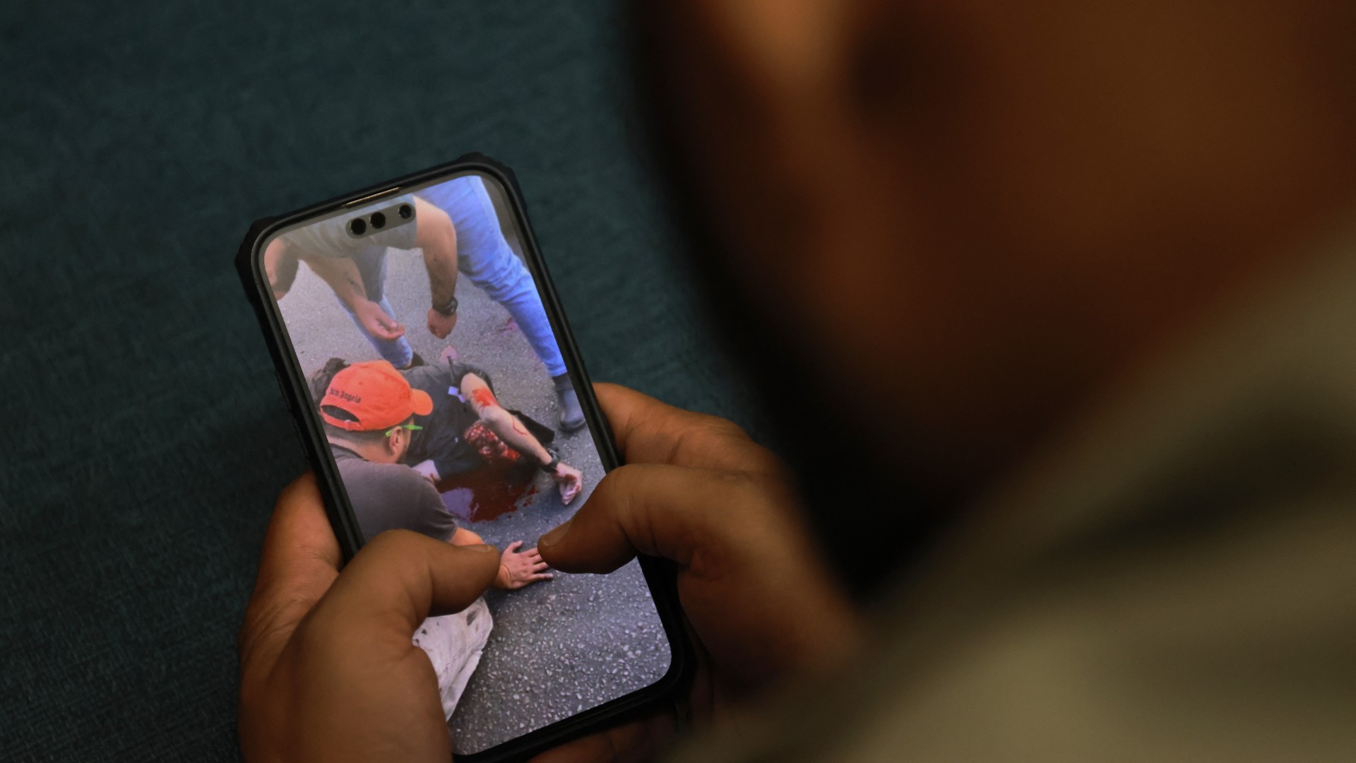 A man watches a video, published on social media, showing a wounded man after explosions hit Hezbollah pagers (Joseph Eid/AFP)