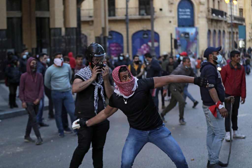 A demonstrator hurls rocks towards the Lebanese parliament on 13 March 2021 (AFP)