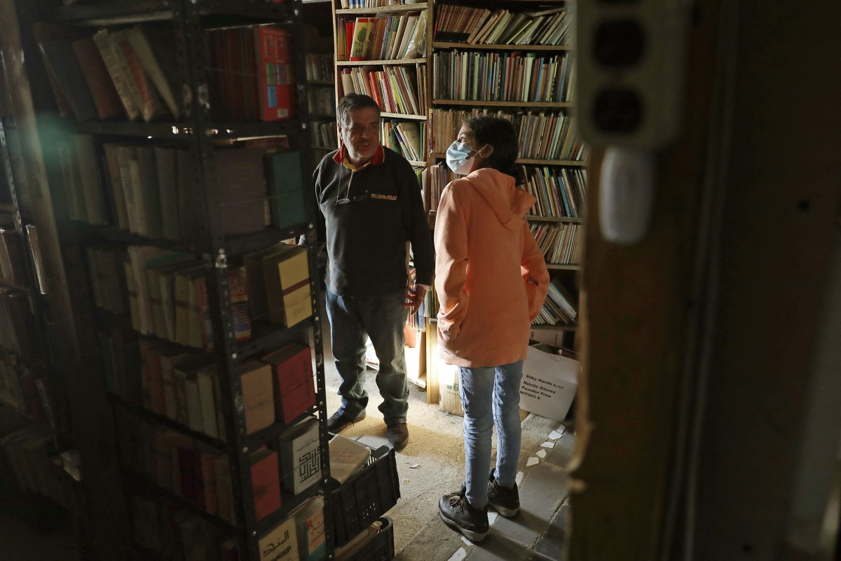Lebanese bookseller Maroun Bechara helps a customer inside his Bazar of Books bookstore in the village of Rachana in northern Lebanon’s Batroun district (AFP)