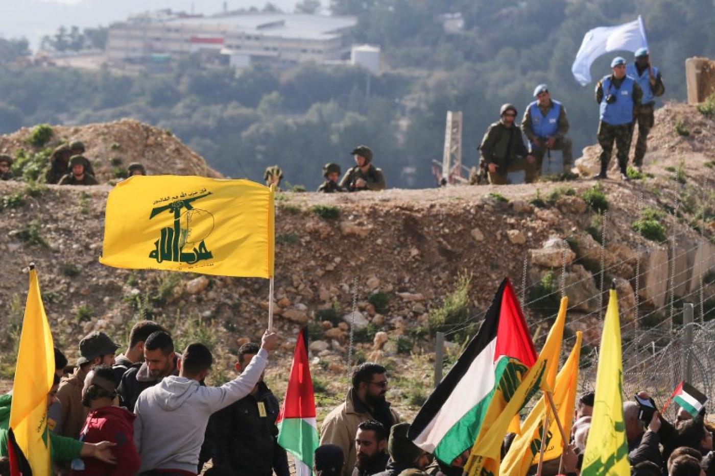 Des soldats israéliens et des Casques bleus observent une manifestation du Hezbollah contre la décision de Donald Trump de reconnaître Jérusalem en tant que capitale d’Israël, dans le village d’Alma al-Shaab, au sud du Liban, le 28 janvier 2018 (AFP)