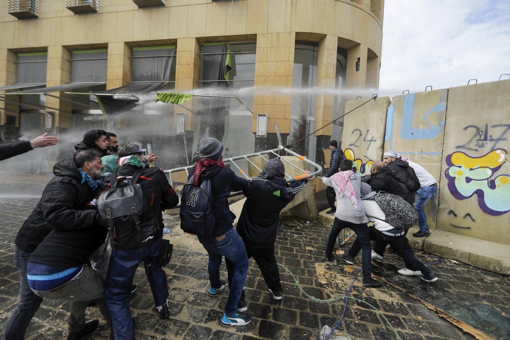 Anti-government protester pull on a section of the cement blocks protecting state institutions in central Beirut during protests on February 11, 2020