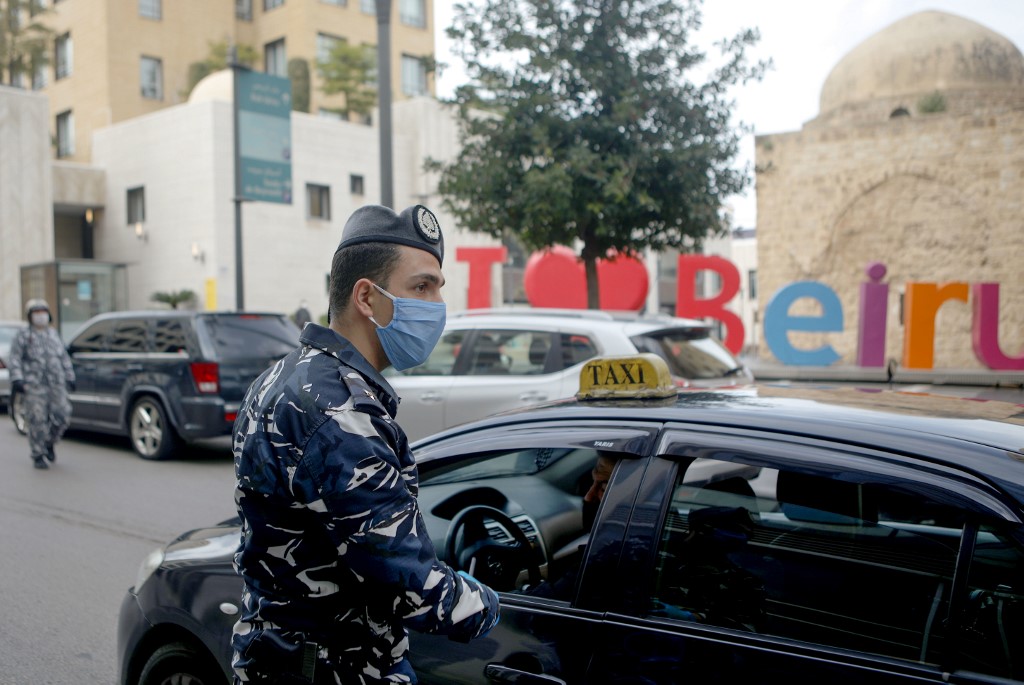 A Lebanese security officer mans a checkpoint to implement a coronavirus curfew in Beirut on 23 March (AFP)