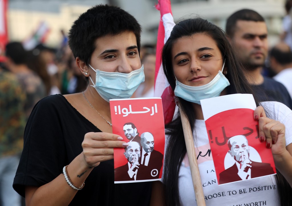 Protesters hold signs with the faces of Lebanese leaders and the word ‘leave’  on 18 October (AFP)