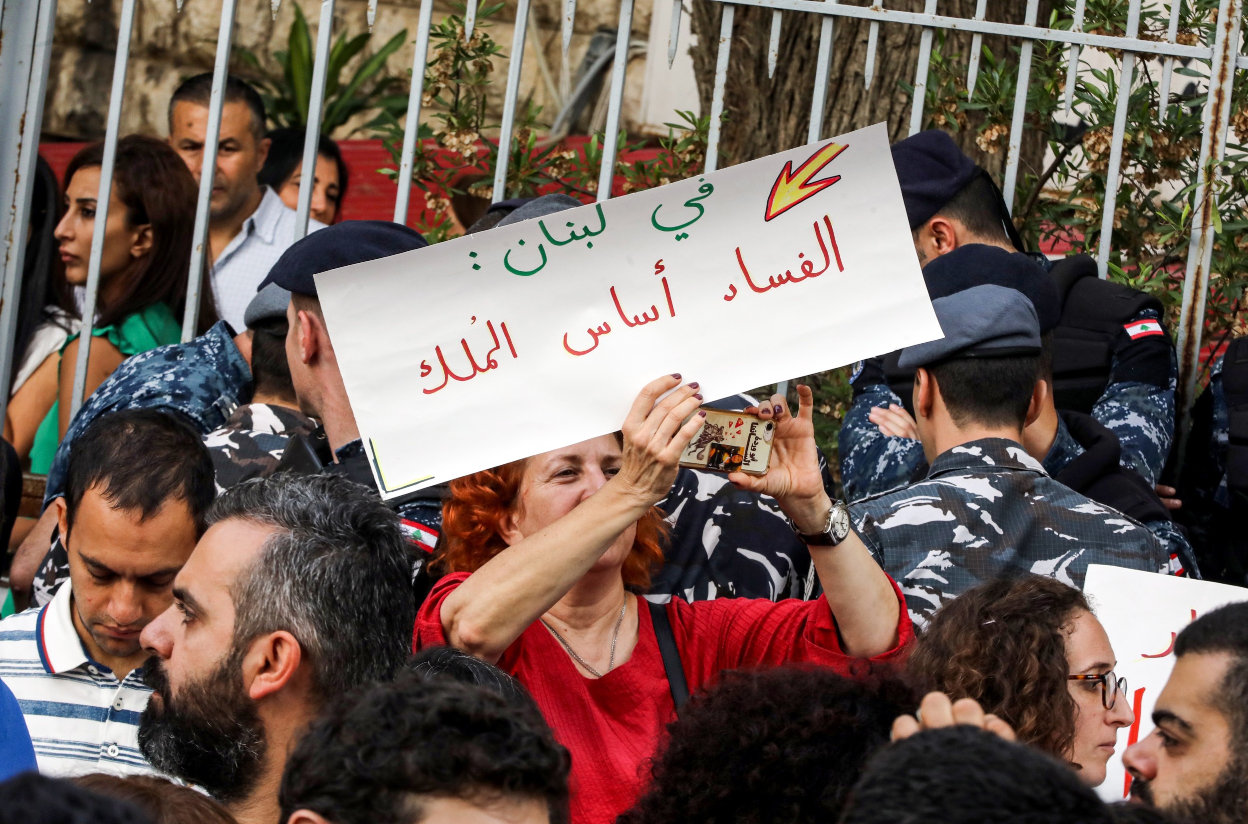 A Lebanese woman holds up a sign reading in Arabic "in Lebanon, corruption is the basis of rule", during a demonstration at the entrance of the Justice Palace in Beirut on 6 November 2019 (AFP)