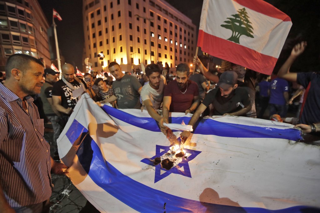 Lebanese protesters set an Israeli flag ablaze during demonstrations on 21 October in Beirut (AFP)