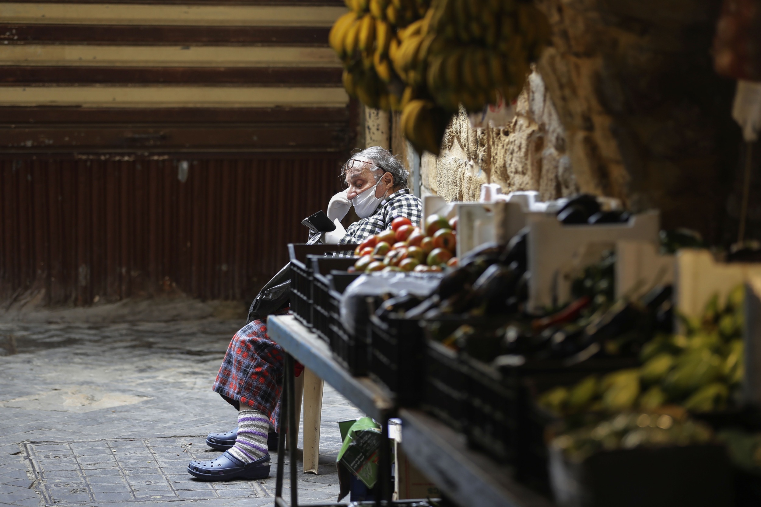 A Lebanese man sits by a fresh produce stall in the market of the historic part of the southern coastal city of Saida on 6 April 2020 (AFP)