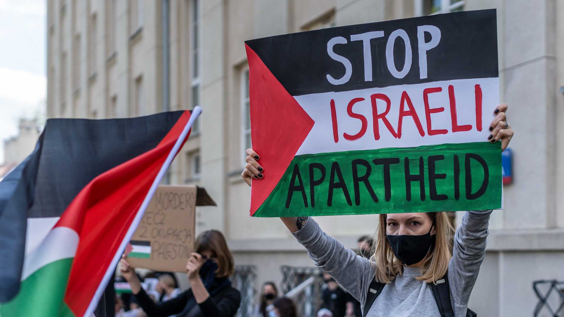 Une femme brandit une pancarte « Stop à l’apartheid israélien » lors d’une manifestation de solidarité avec les Palestiniens, le 15 mai 2021 (AFP)