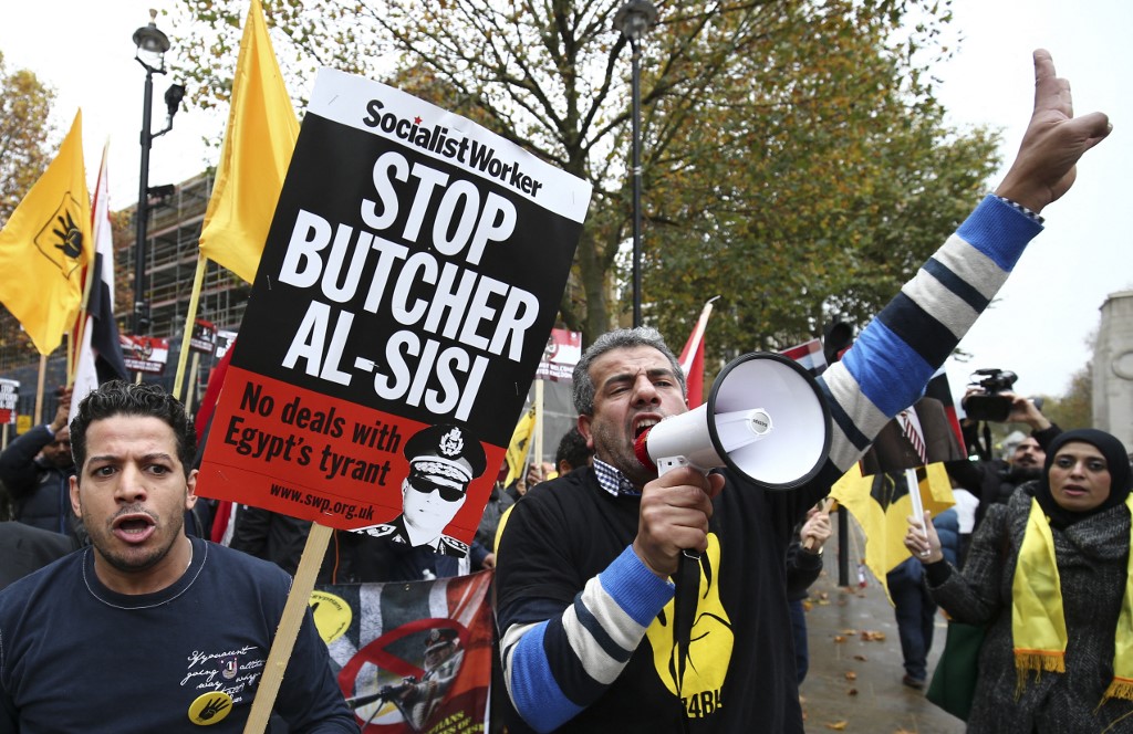Protesters in London denounce Egyptian President Abdel Fattah al-Sisi and wave placards showing the four-finger symbol associated with the Rabaa massacre on 5 November 2015 (AFP)