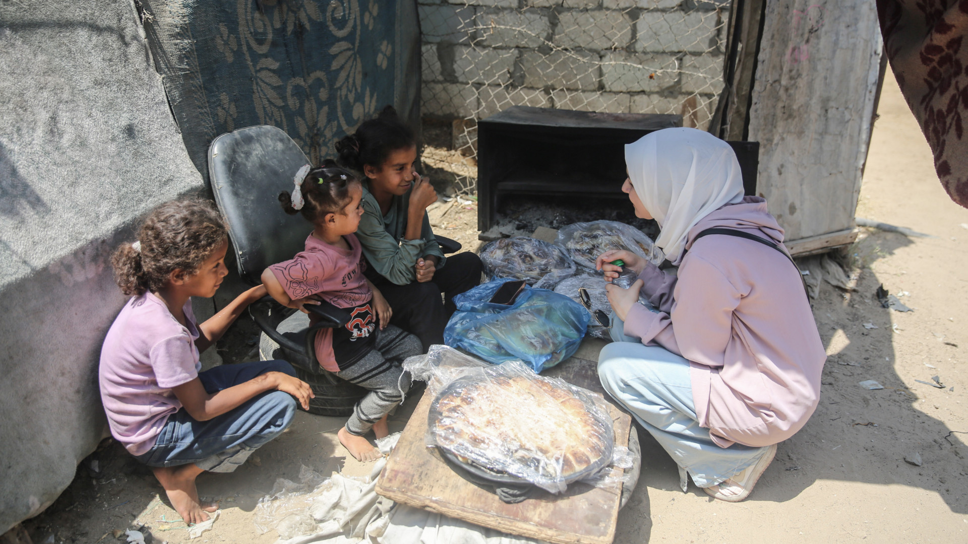 Maha Hussaini (R) interviewing Palestinian girls at a displacement camp in the central Gaza Strip on 3 June 2024 (MEE/Mohammed al-Hajjar)