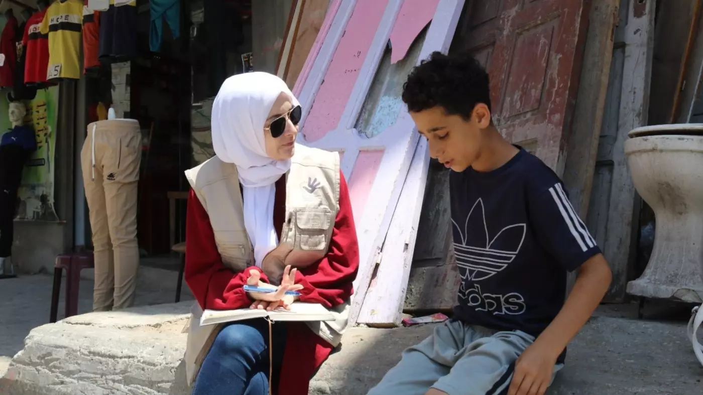Maha Hussaini (L) interviewing a Palestinian boy in the Gaza Strip in June 2023 (Mahmoud Mushtaha)