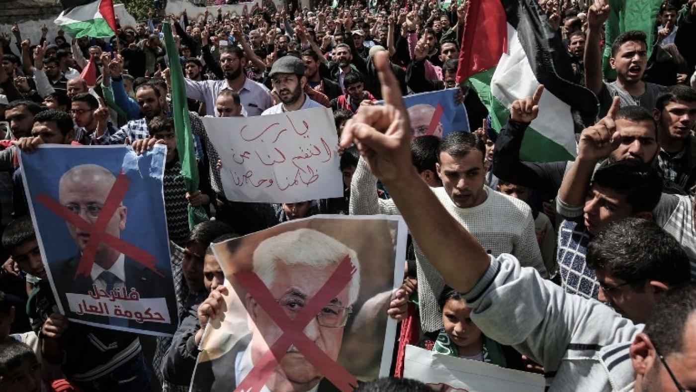 Demonstrators in Gaza hold up portraits of Mahmoud Abbas in protest against the PA president (AFP) 