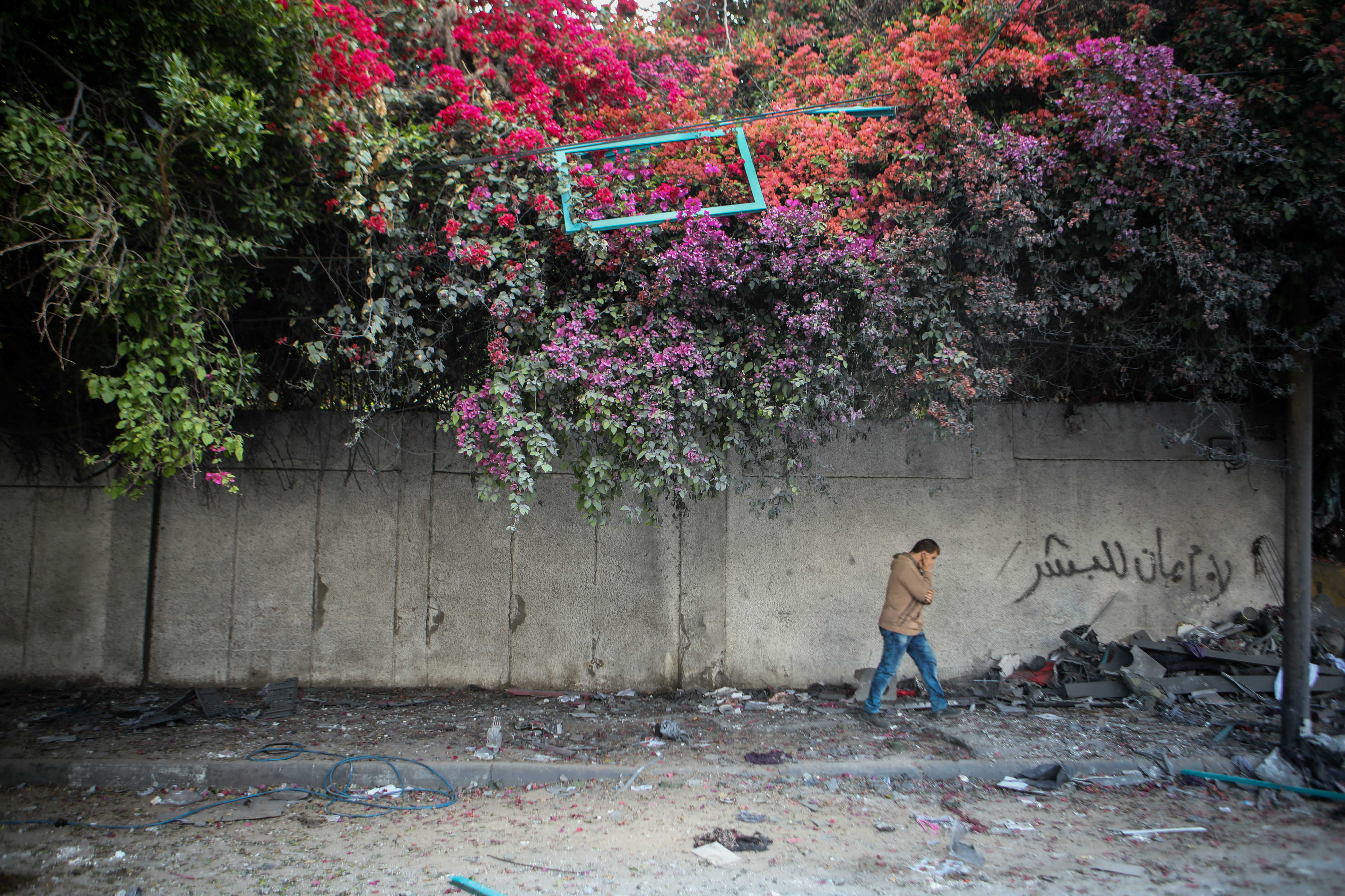A man walks down a street in Gaza littered with debris cause by Israeli strikes (MEE/Mohammed al-Hajjar)