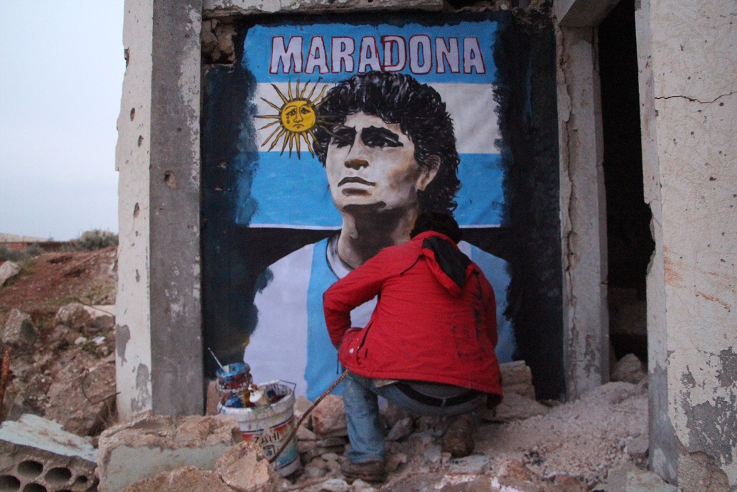L’artiste syrien Aziz Asmar peint un mur à l'’effigie de Maradona dans la ville de Binnish,  province d’Idleb  (MEE/Ibrahim Yasouf)