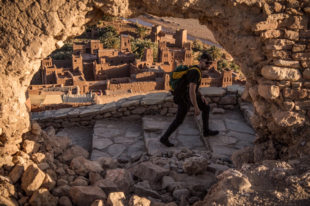 Un touriste se promène près de la Kasbah (ancienne forteresse) d’Aït-Ben-Haddou (en arrière-plan), où des scènes représentant la ville fictive de Yunkai de la série à succès Game of Thrones ont été tournées, à environ 32 km au nord-ouest de la ville de Ouarzazate, dans le Haut Atlas marocain, le 27 janvier 2020 (AFP/Fadel Senna)