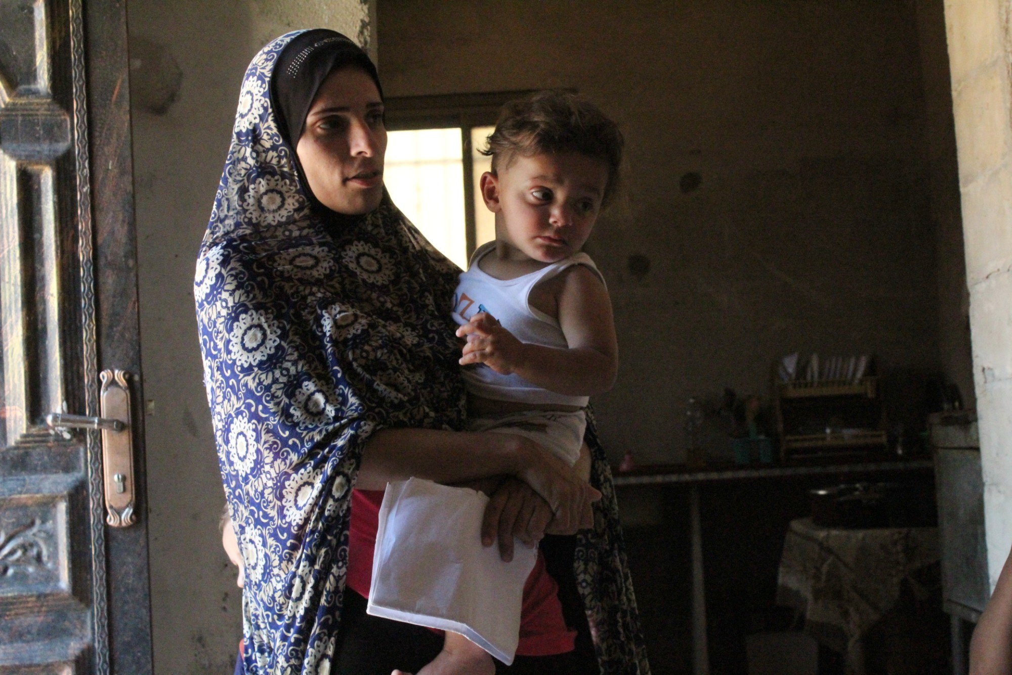 Maye Barakat tient dans ses bras son fils d’un an et demi, qui a des problèmes respiratoires, et ses papiers médicaux (MEE/Megan Giovannetti)