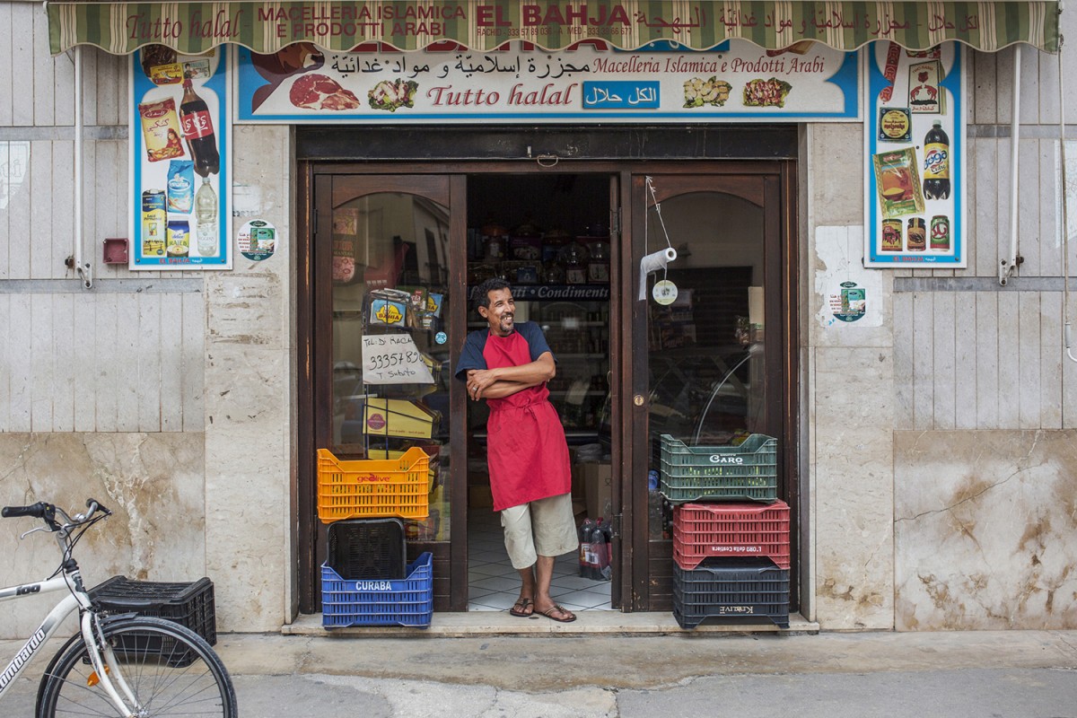 A man stands outside a halal butcher in the Sicilian village of Mazaro del Vallo (MEE/Alessio Mami)