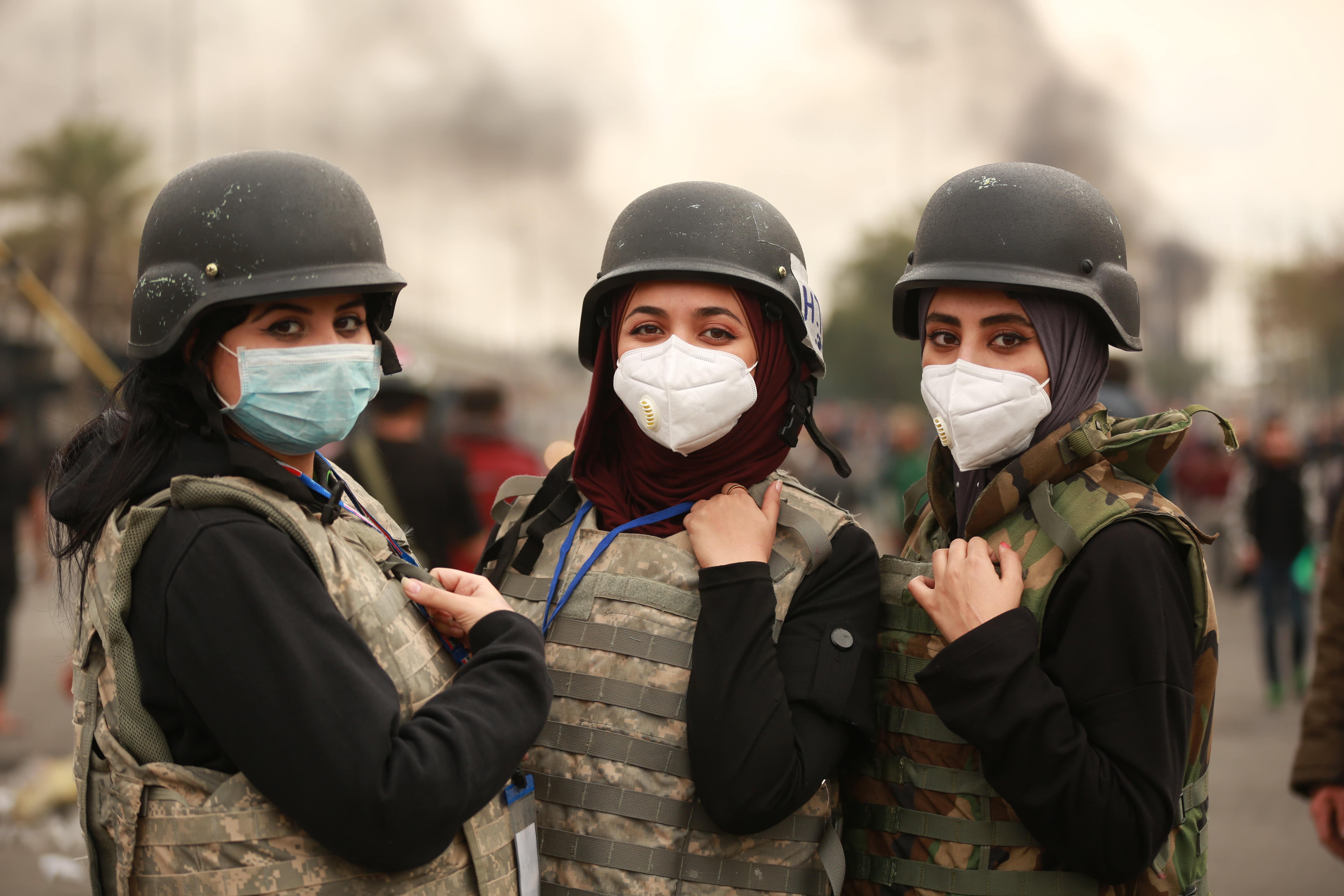 Des étudiantes en médecine portant des masques chirurgicaux se tiennent à peu de distance des gaz lacrymogènes tirés sur les manifestants (MEE/Ali Dab Dab)