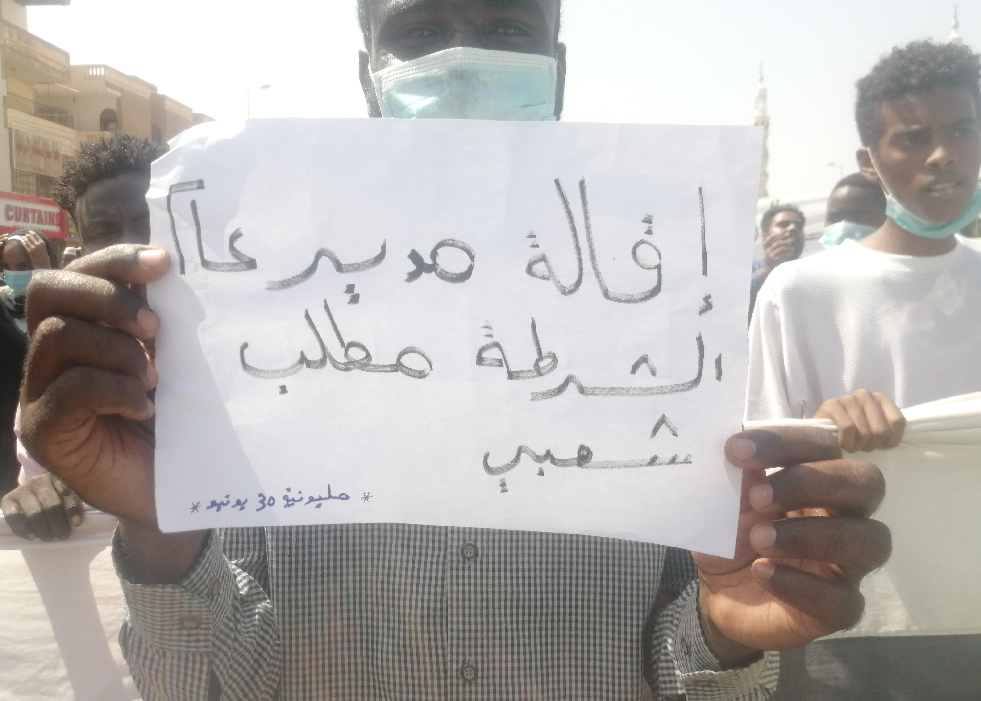 A man is holding up a sign during protests in Sudan.