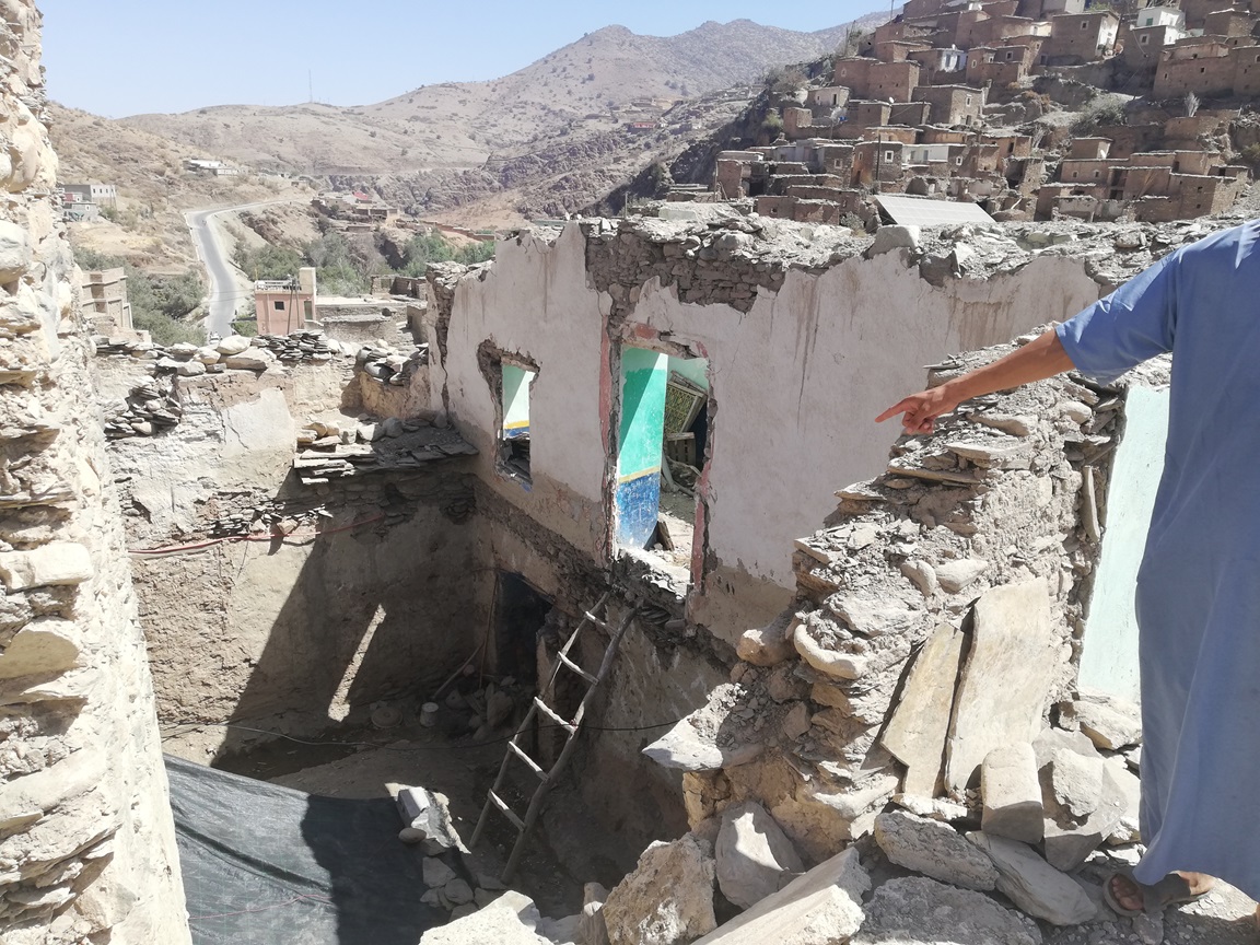 A young man shows his architect around the rubble of his house in this region known for its earth and stone buildings that blend into the landscape (provided)