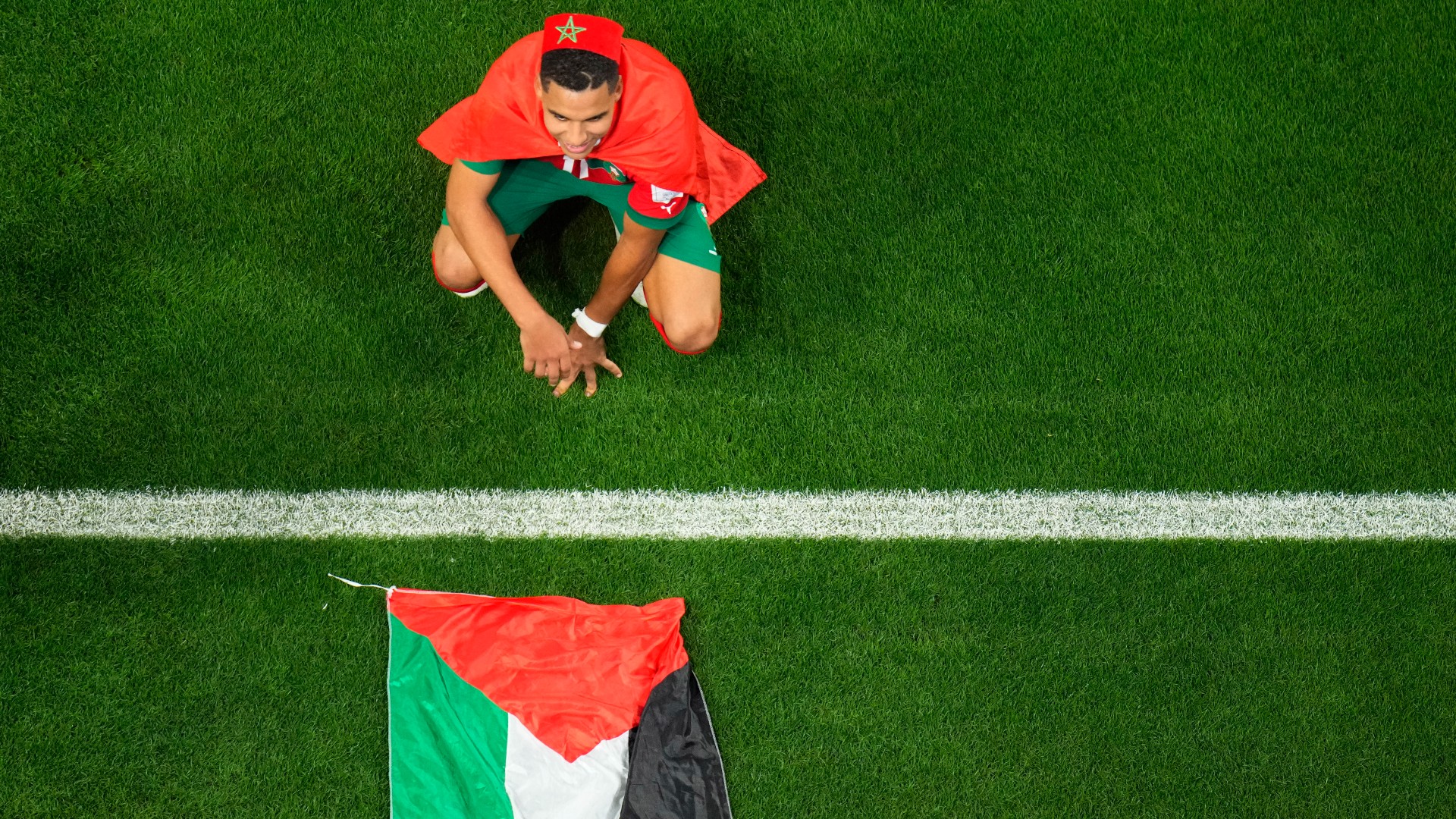 Morocco's Abdelhamid Sabiri celebrates near the Palestinian flag after the Atlas Lions' World Cup victory over Spain at the Education City Stadium in Al Rayyan, Doha on 6 December 2022 (Associated Press)