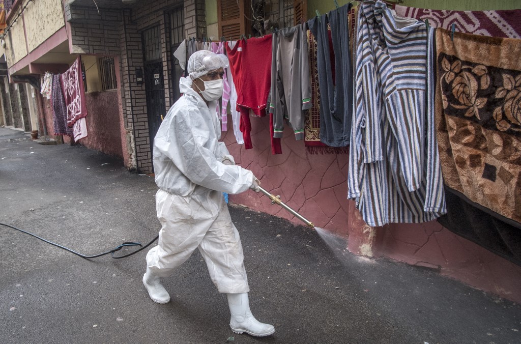 A Moroccan health ministry worker disinfects a street in Rabat on 9 April (AFP)