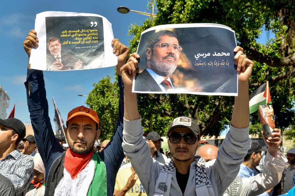 Protesters hold up portraits of Morsi during a demonstration in Rabat on 23 June (AFP)