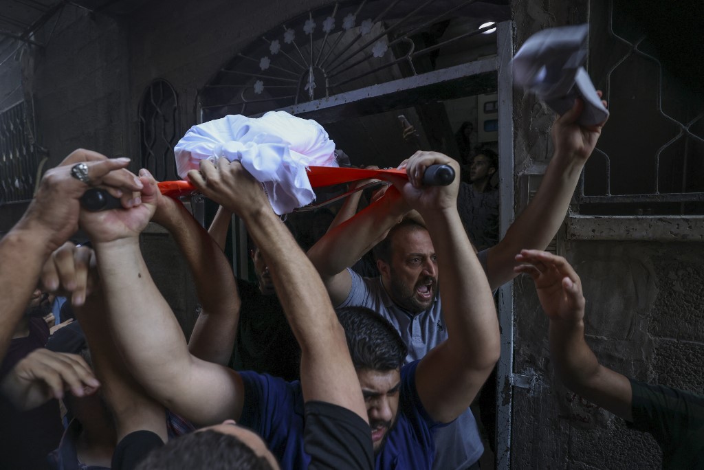 Mourners carry the body of a Palestinian boy killed by Israeli forces in northern Gaza on 8 August 2022 (AFP)