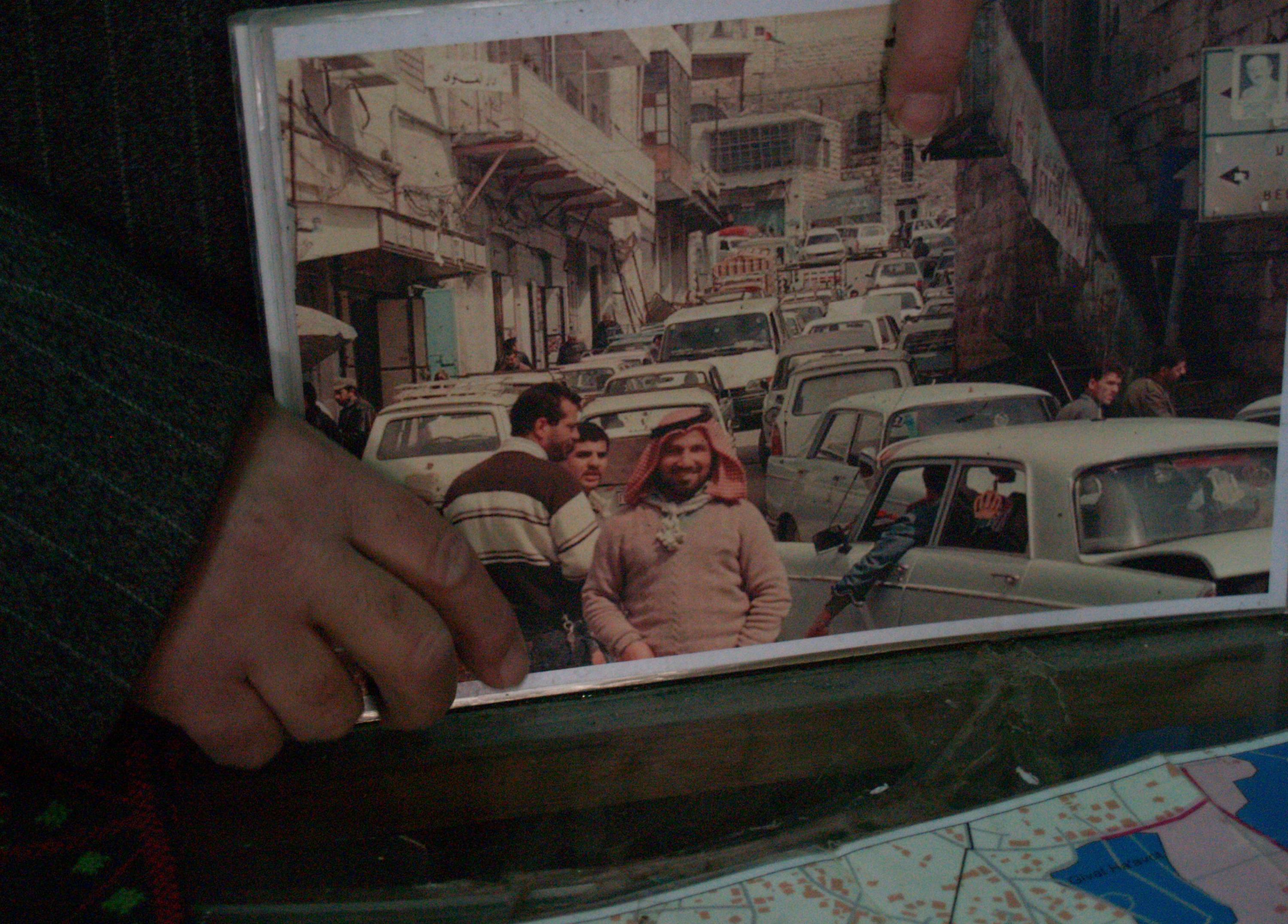Munir shows a photo of Shuhada Street in the days before the massacre, back when the road was the bustling centre of Hebron (MEE/Megan Giovannetti)