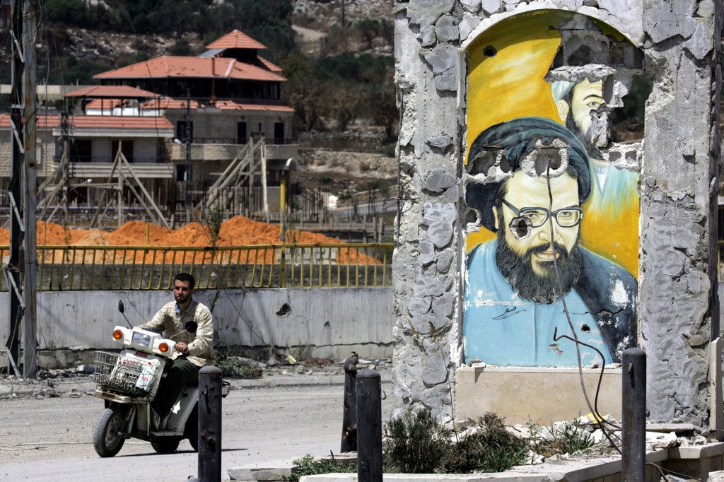 A motorcycle passes a ruined portrait of late Hezbollah leader Abbas Musawi, who was killed in an Israeli operation in 1992, in the southern Lebanese town of Bint Jbeil in 2006 (AFP)