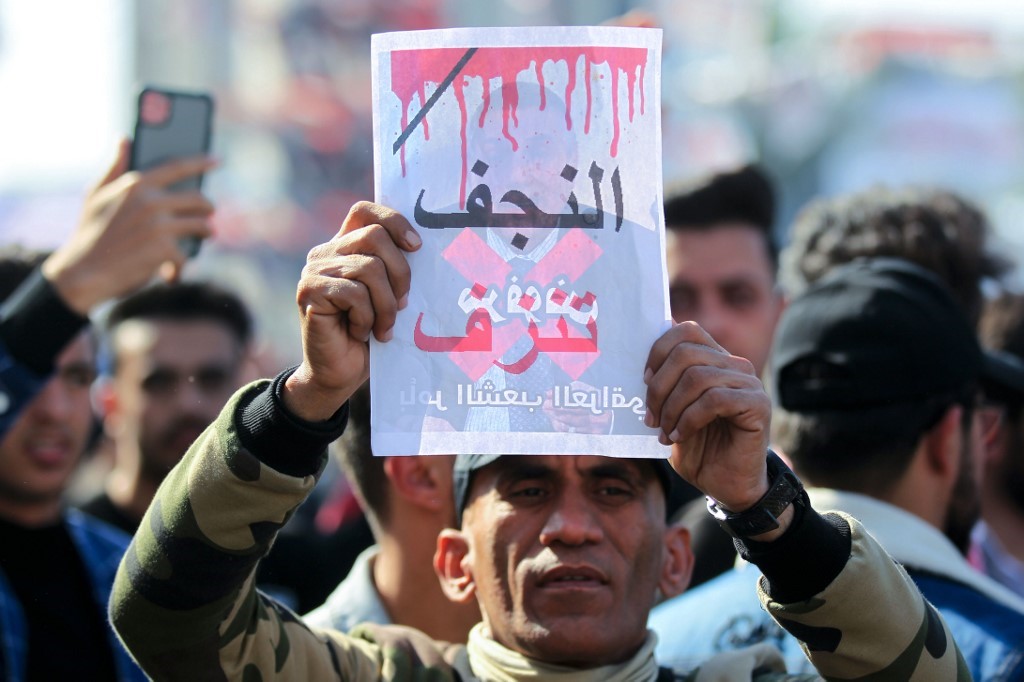 An Iraqi protester lifts a placard with the inscription "Najaf is bleeding", during an anti-government demonstration in Baghdad's Tahrir square, on 6 February (AFP)