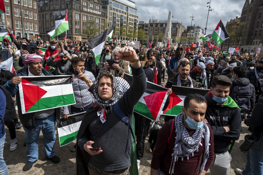 Protesters wave Palestinian flags in Amsterdam on 16 May 2021 (AFP)