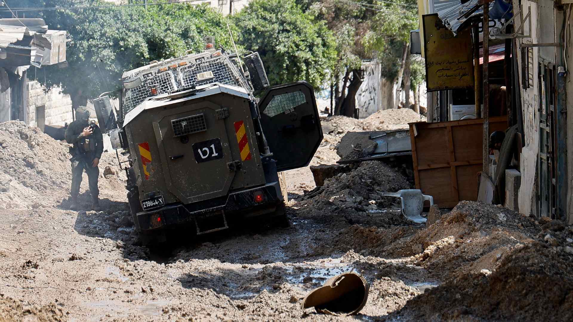 An Israeli soldier stands next to a military vehicle during a raid in Nur Shams on 23 July 2024 (Raneen Sawafta/Reuters)