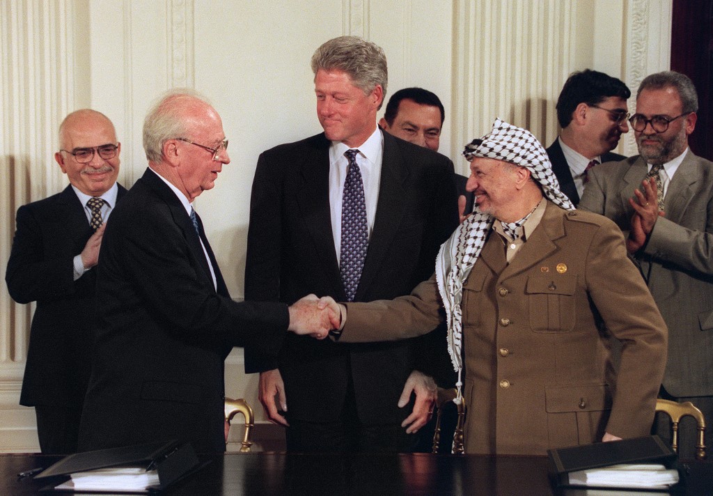 Former US President Bill Clinton observes as former Israeli Prime Minister Yitzhak Rabin and former PLO chairman Yasser Arafat shake hands in Washington in 1995 (AFP)