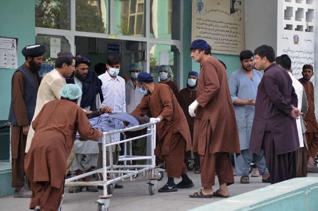 People along with a medical team carry a wounded man on a stretcher following border clashes between Afghan Taliban and Pakistani forces, at Mirwais hospital in Kandahar on February 24, 2022.