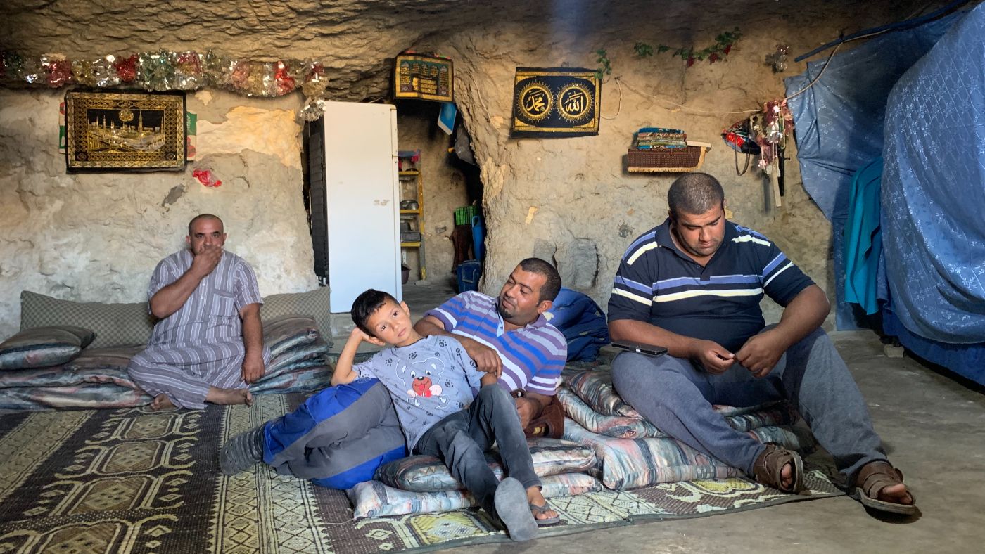 Brothers (from left) Mustafa, Othman and Mohammad Abu Qbeita sit with their children in a cave that serves as a home due to an Israeli ban on construction in the area (MEE/Shatha Hammad)