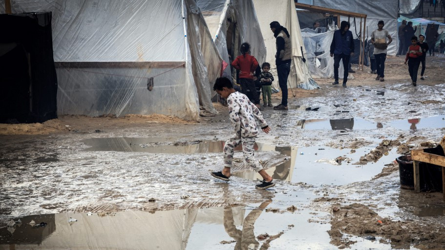 A Palestinian child walks past tents at a makeshift camp housing displaced Palestinians, in Rafah in the southern Gaza Strip, on 2 January 2024 (AFP)