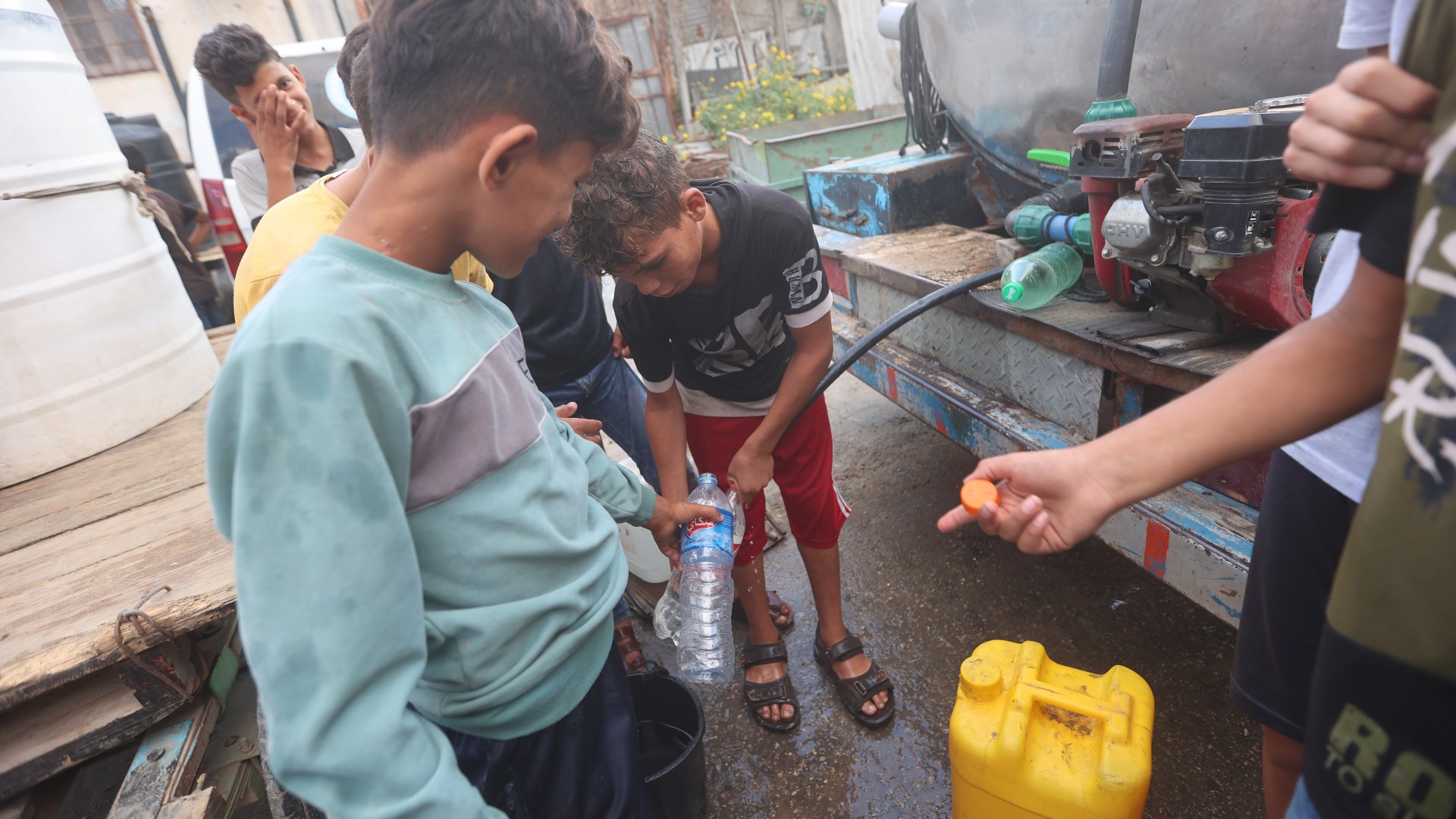 Palestinian children fill up containers from a potable water truck in Gaza City on 15 October 2023 (MEE/Mohamed Hussein)