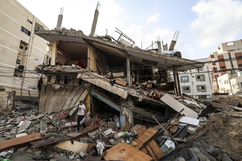 Palestinians salvage belongings from the rubble of their home after Israeli planes bombed Gaza on 7 August 2022 (AFP)