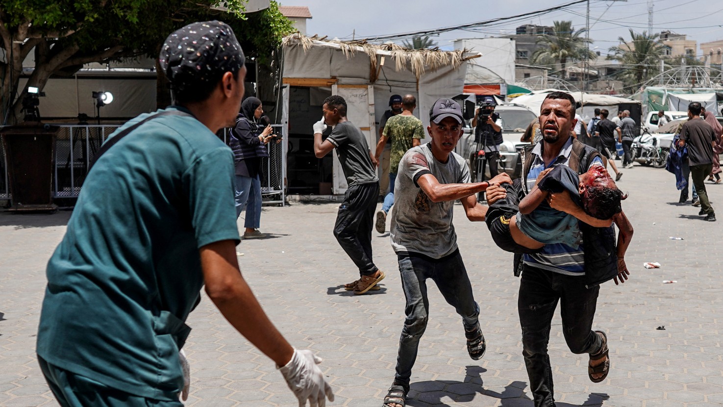 A medic waits as a man carrying an injured girl rushes to the al-Aqsa Martyrs Hospital in Deir al-Balah following heavy Israeli air strikes in the area on 8 June, 2024 (Bashar Taleb/AFP)