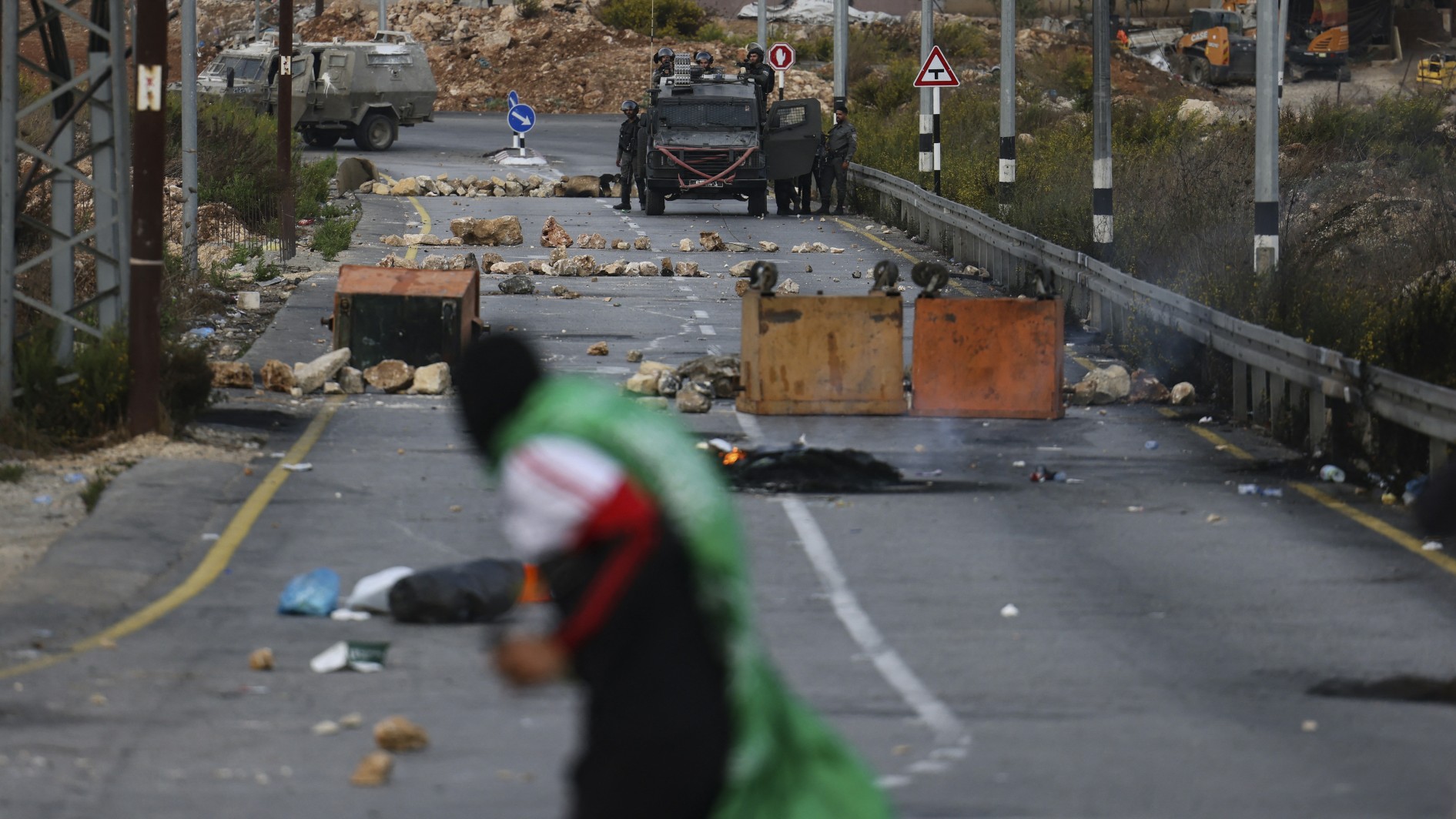 A Palestinian protester hurls rocks towards Israeli security forces during confrontations at the northern entrance to the occupied West Bank city of Ramallah, on October 12, 2022.