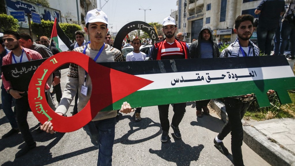 Palestinians march with a giant key-shaped sign showing the colours of the Palestinian flag and the slogan ‘Return is a sacred right’ in Gaza in May 2019 (AFP)