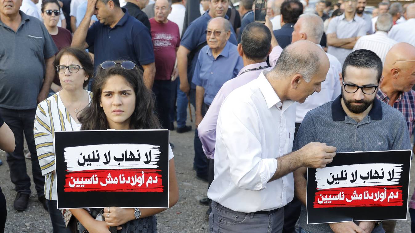 Arab Israeli protesters carry placards reading in Arabic, "revenge destroys home, courts are the solution" as they protest outside the district police headquarters in the Arab Israeli city of Nazareth during a demonstration against violence, organised crime and recent killings among their communities, on October 22, 2019.