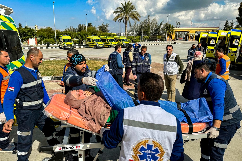 An injured Palestinian woman reacts as she is transported on a gurney by Egyptian Red Crescent paramedics after evacuation from the Gaza Strip via the Rafah border crossing into Egypt on February 3, 2024